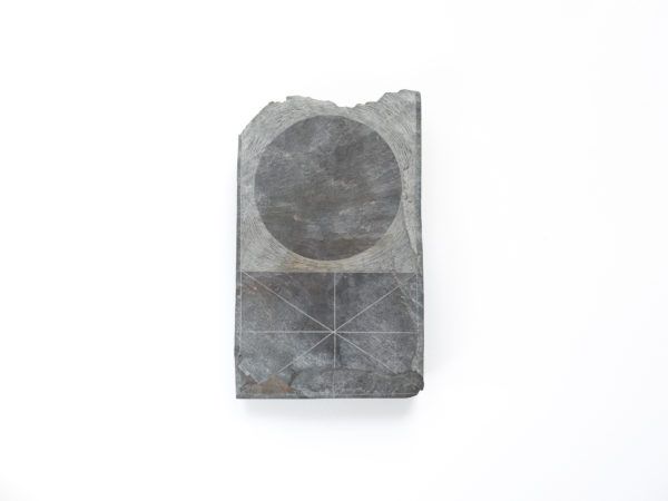 A gray stone plaque with a circular top and etched geometric lines on a white background