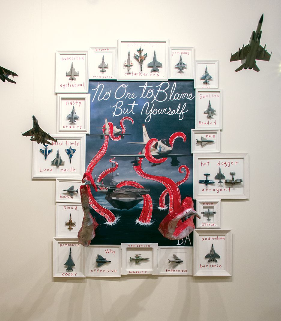 Wall display of paper airplanes framing a sign reading “No One to Blame But Yourself” with a red octopus
