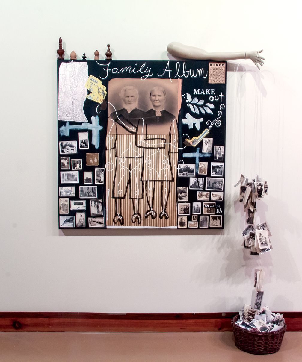 Family album wall display with black frame, sepia portrait, and small photo collage in a white room