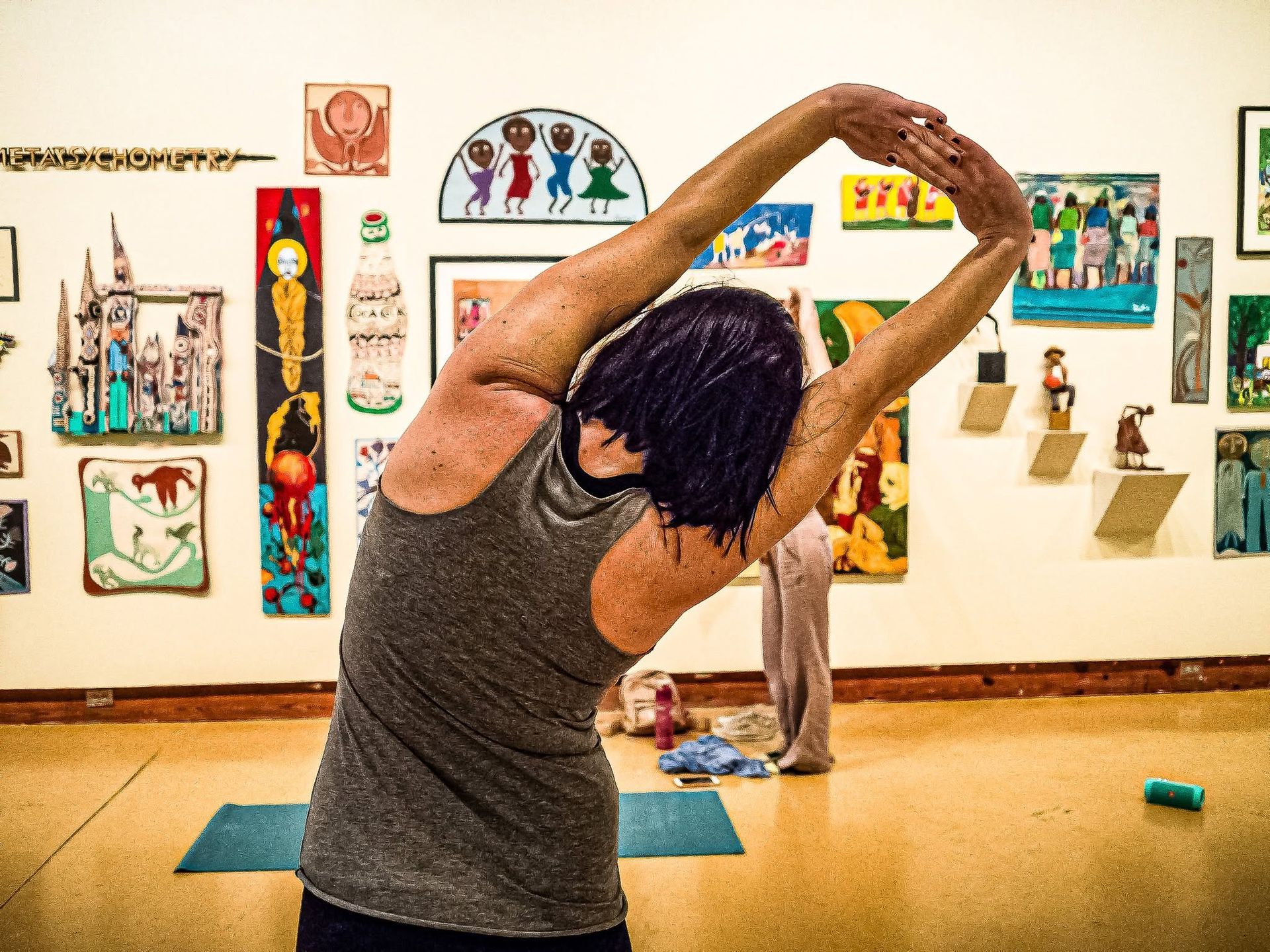 Person stretching in a yoga pose in an art gallery with colorful wall artworks.