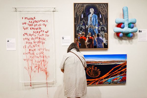 Gallery wall with abstract works, a framed portrait, and a person viewing a landscape print