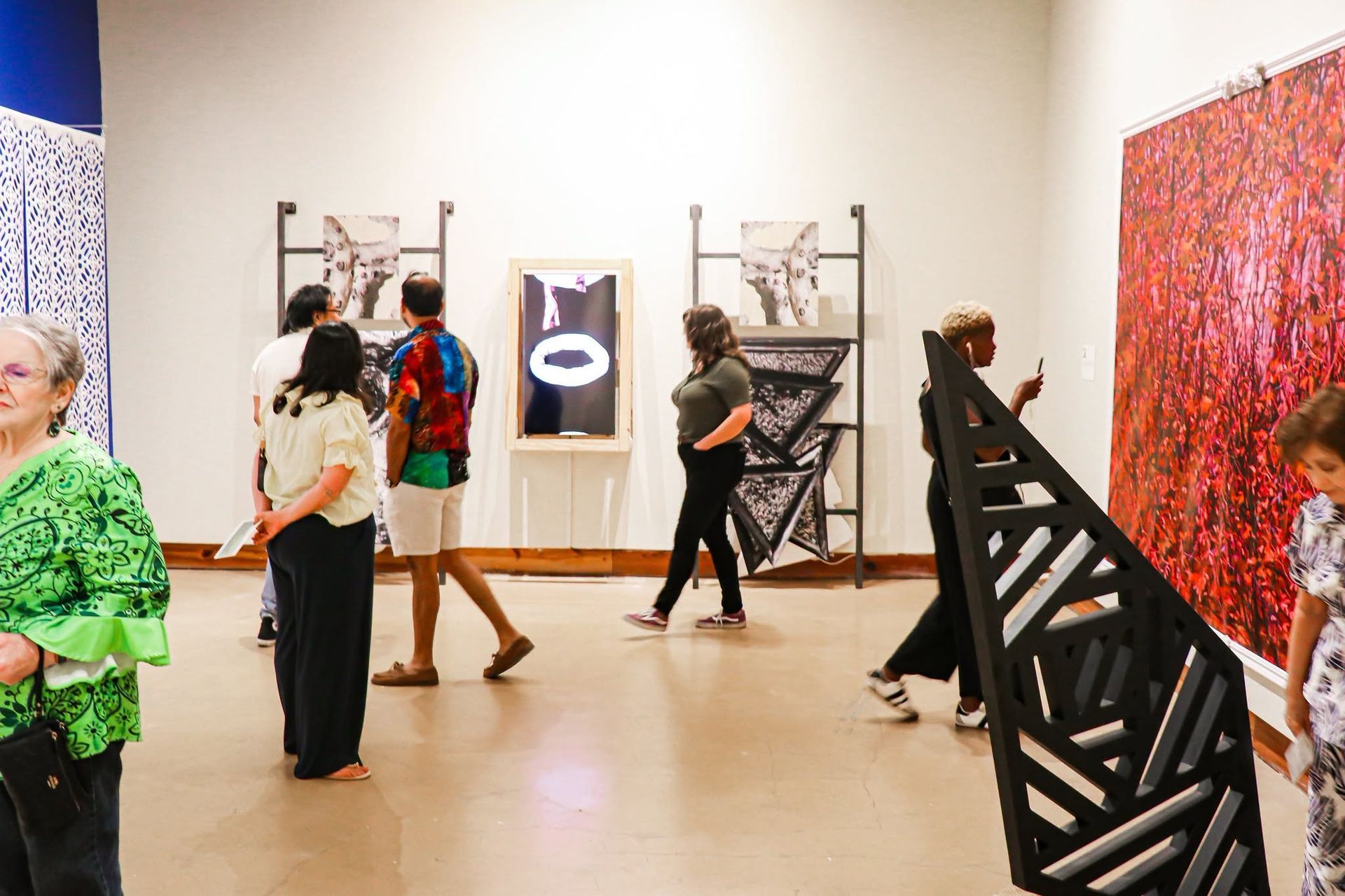 People viewing abstract art in a bright gallery, with colorful paintings and sculptures on display