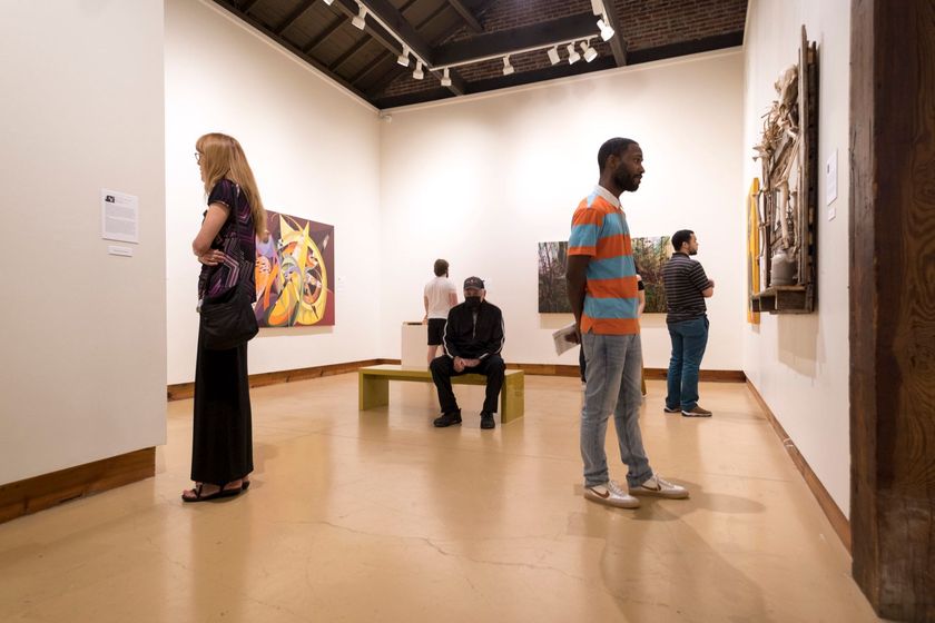 People viewing artwork in a modern art gallery with white walls and polished floors
