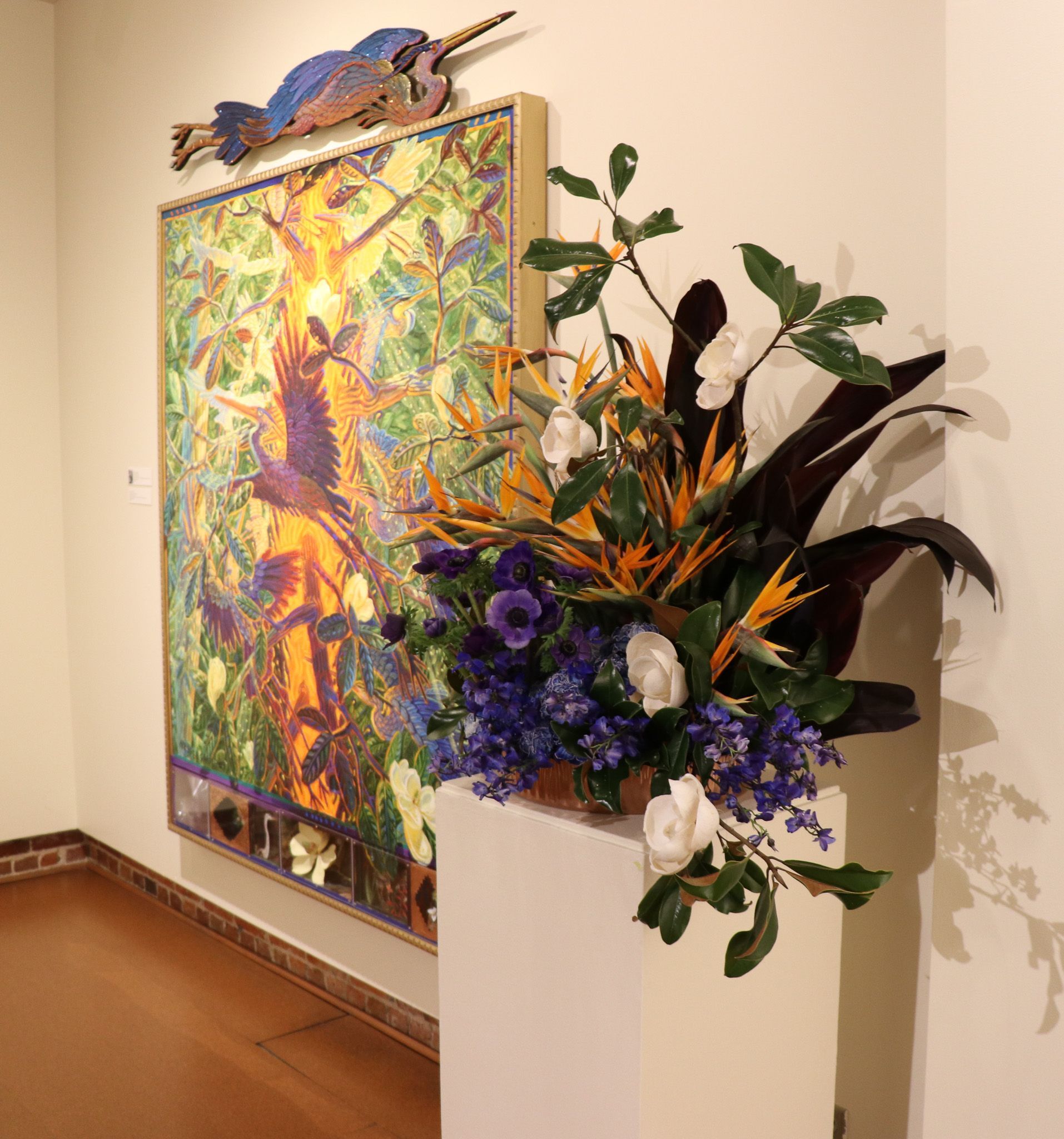 Colorful floral arrangement beside an abstract painting in a gallery hallway