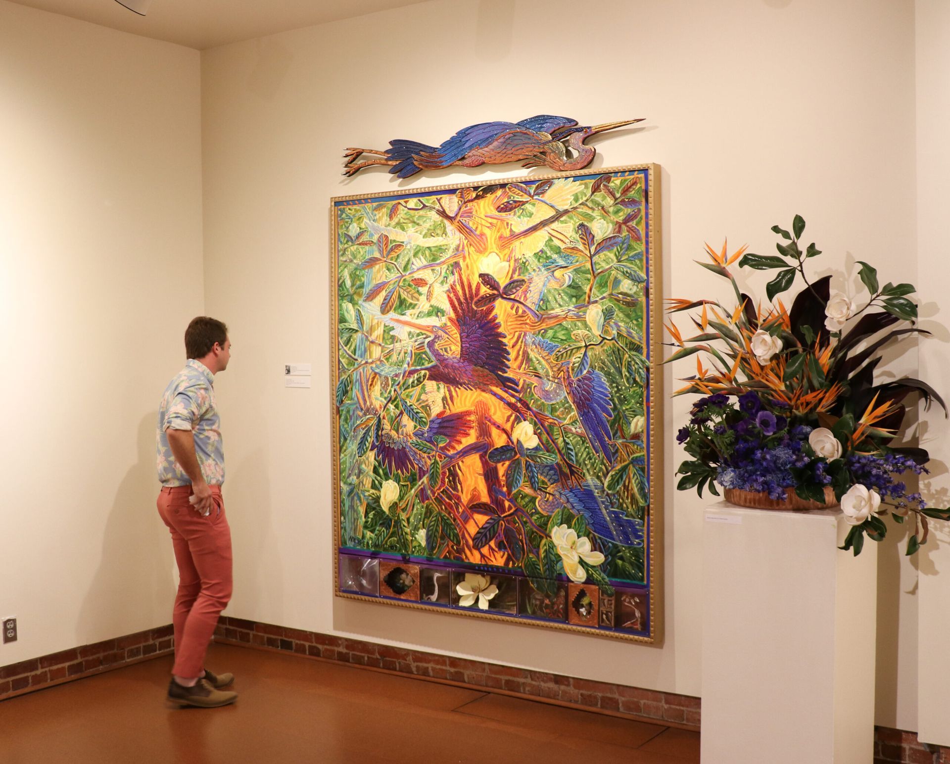 Person viewing a large colorful abstract painting in a gallery hallway.