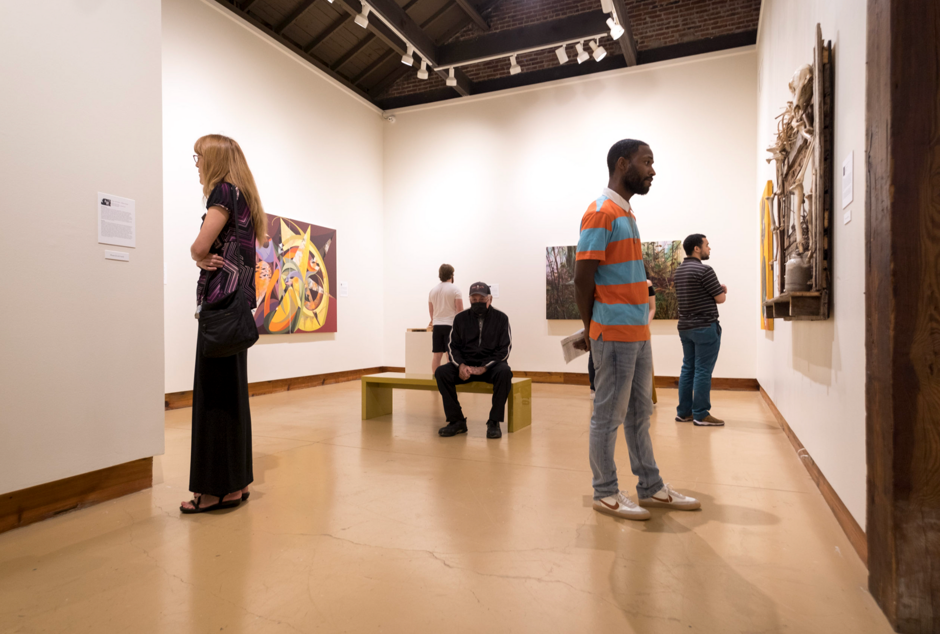 People viewing artworks in a museum gallery with paintings on white walls