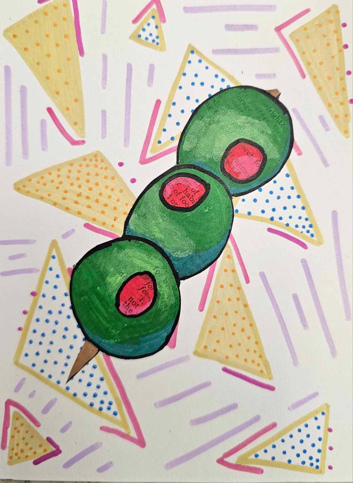 Three green olives with red pimentos on toothpicks against a pastel confetti background