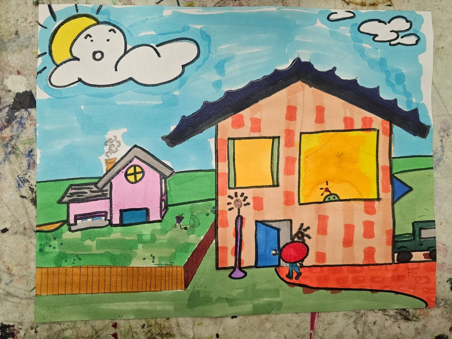 Childlike drawing of two colorful houses under a blue sky with clouds and a sun, with a small person in front.