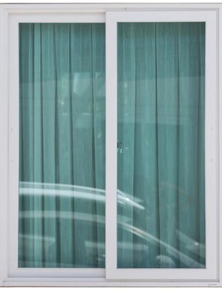 White sliding window with teal curtains behind it