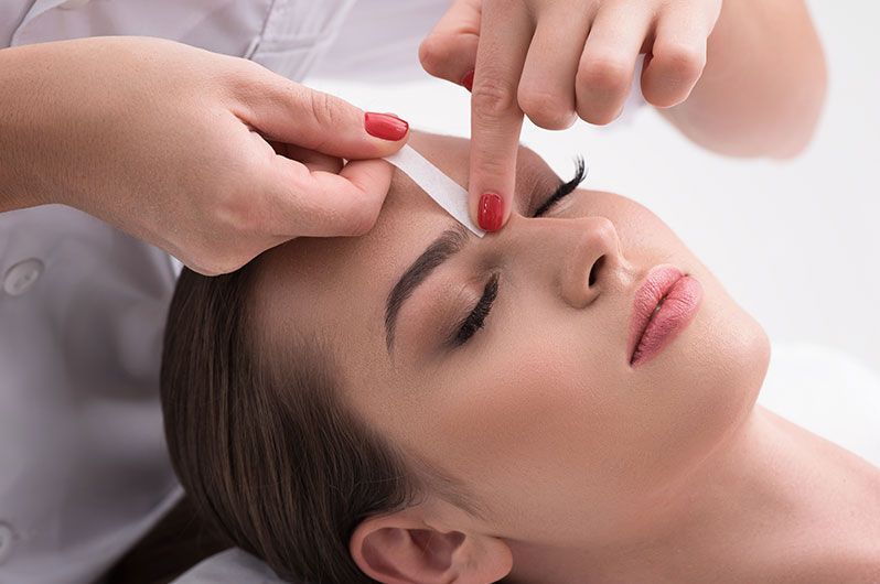 A woman is getting her eyebrows waxed in a beauty salon.