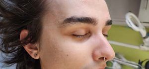 A close up of a man 's face with his eyes closed and a nose ring.