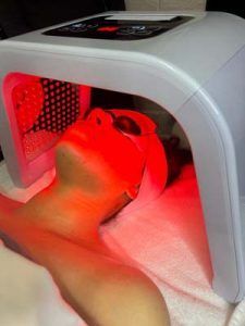 A woman is getting a red light treatment on her face.