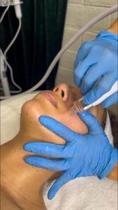 A person wearing blue gloves is getting a facial treatment.