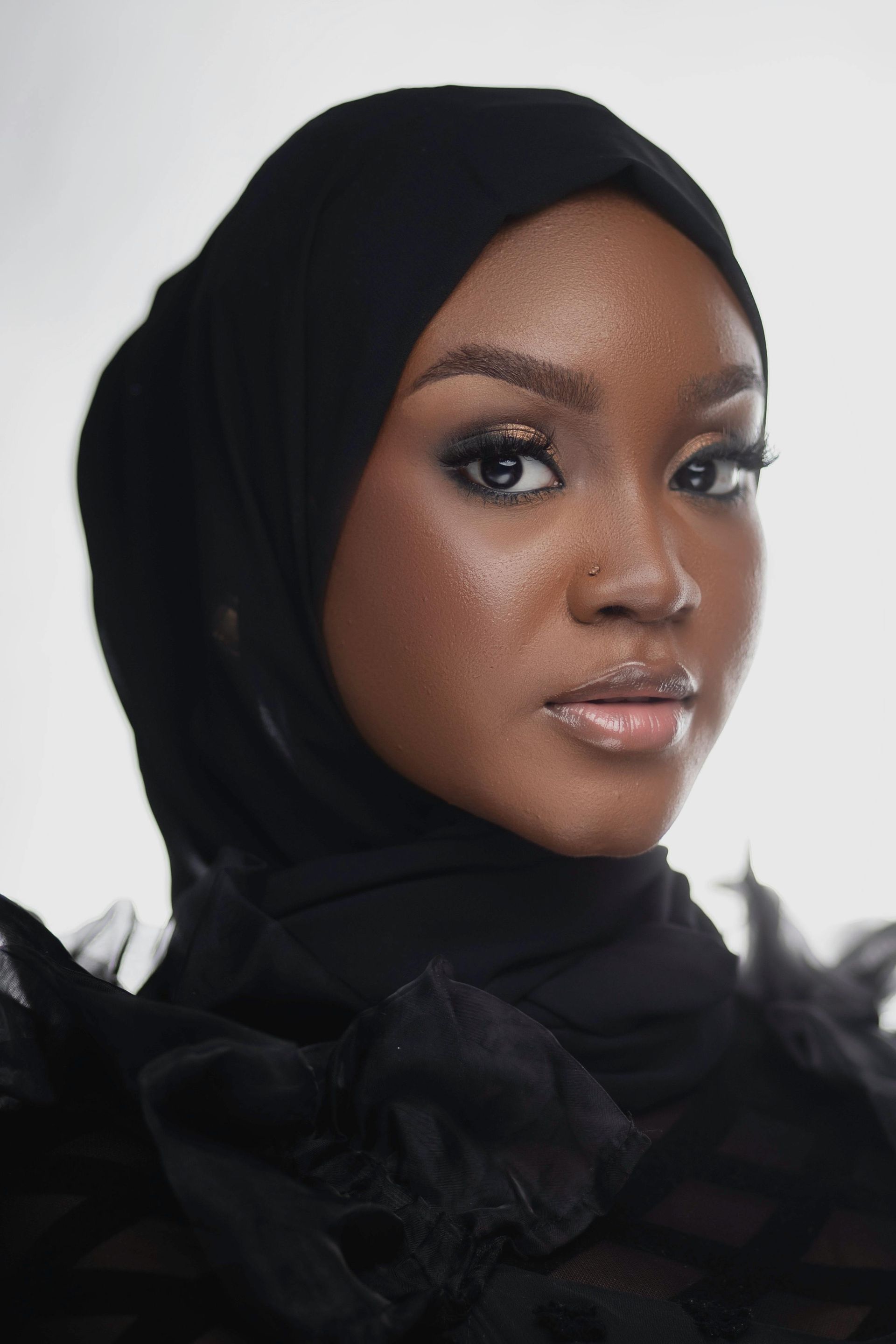 A woman wearing a black hijab looks at the camera