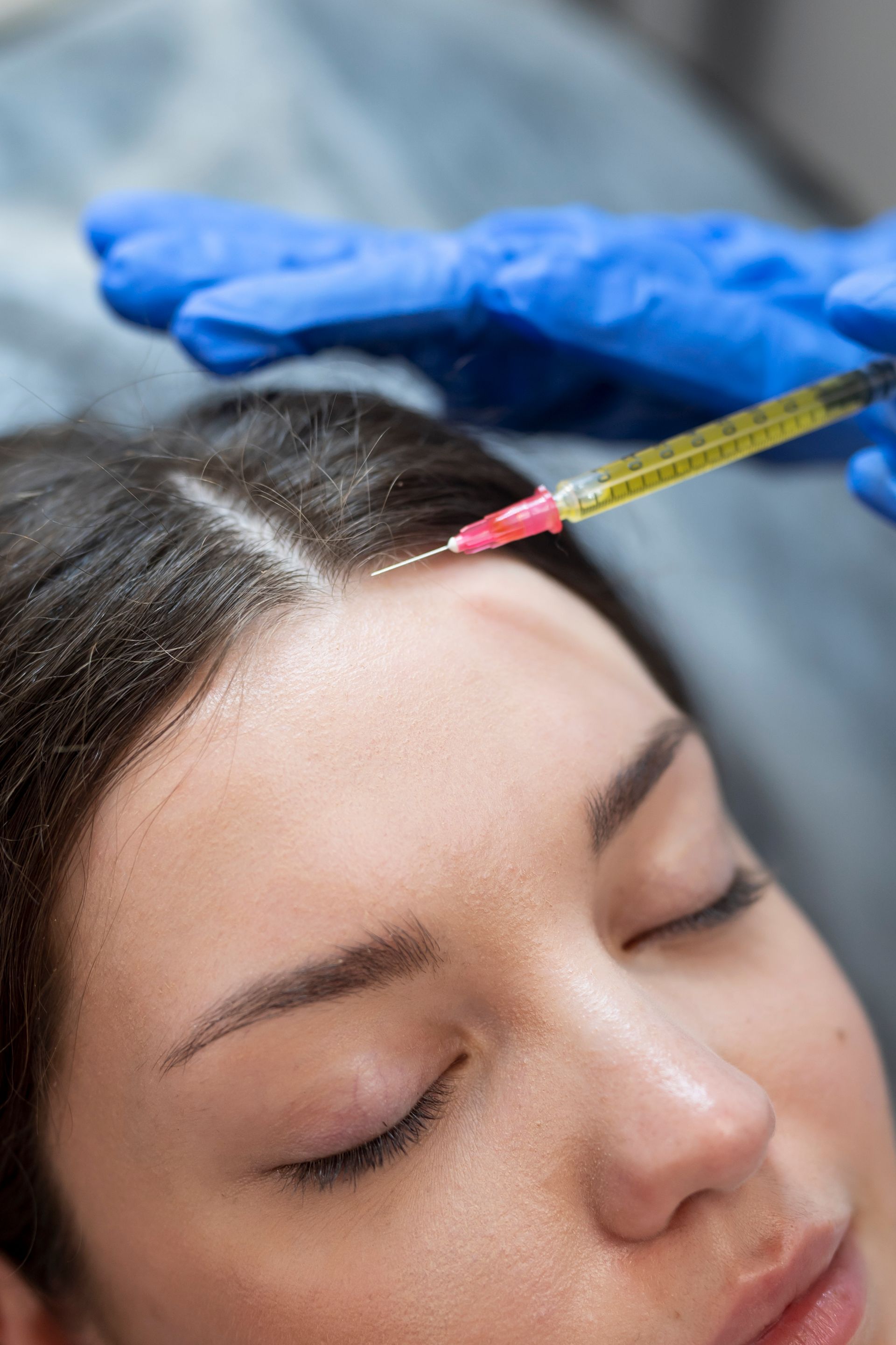 A woman is getting an injection in her hair.