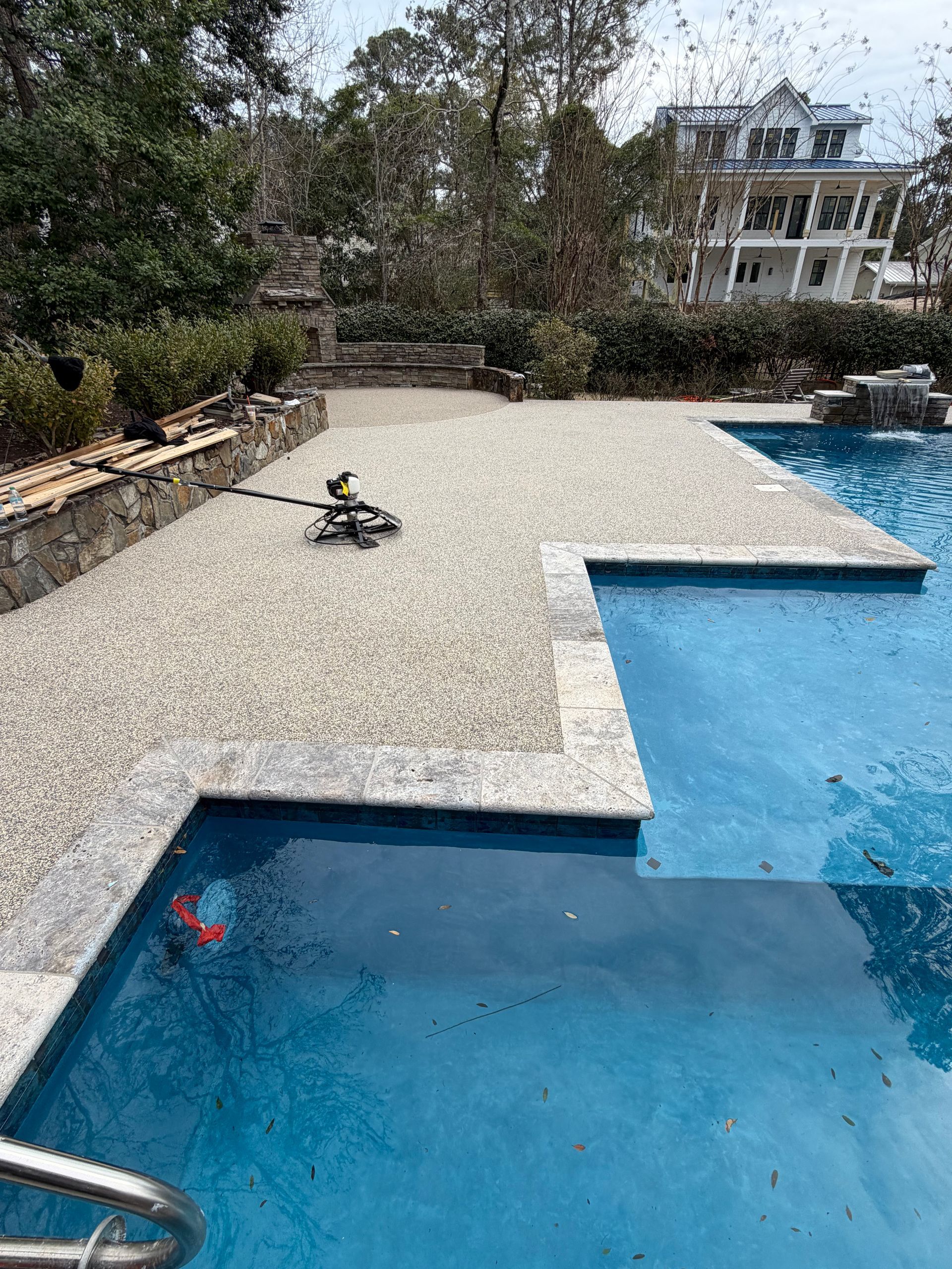Backyard pool with a blue water ledge and a small toy car on the patio.