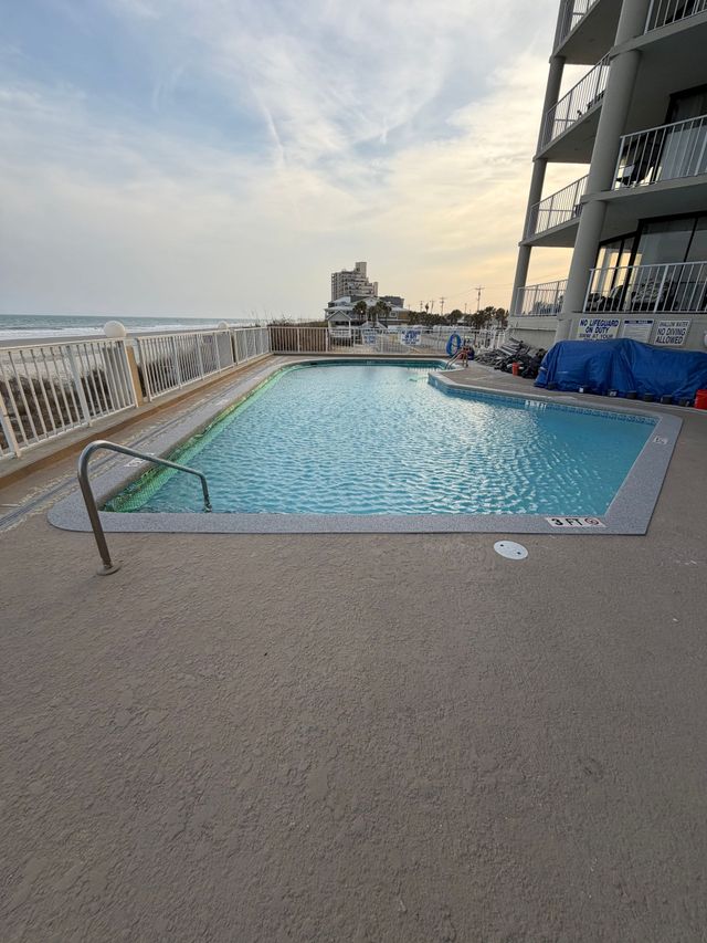 Rooftop pool with ocean view at sunset beside a modern building
