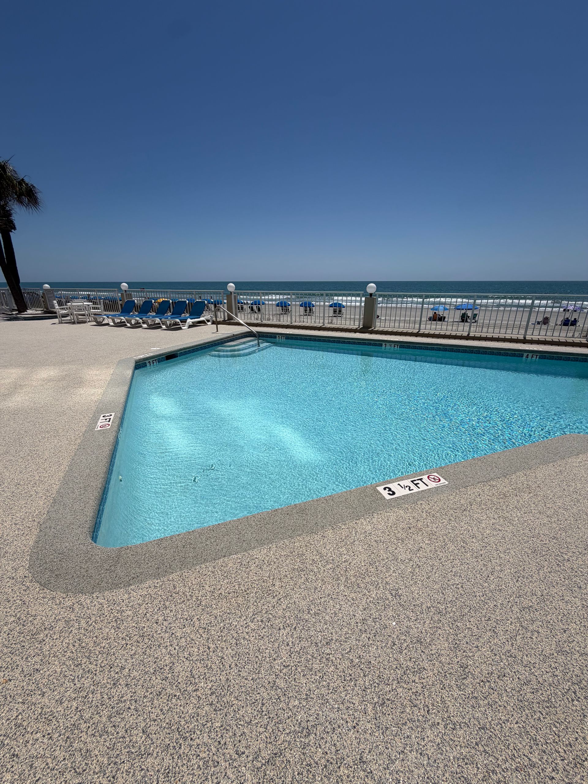 Sunny seaside pool beside the ocean under a clear blue sky