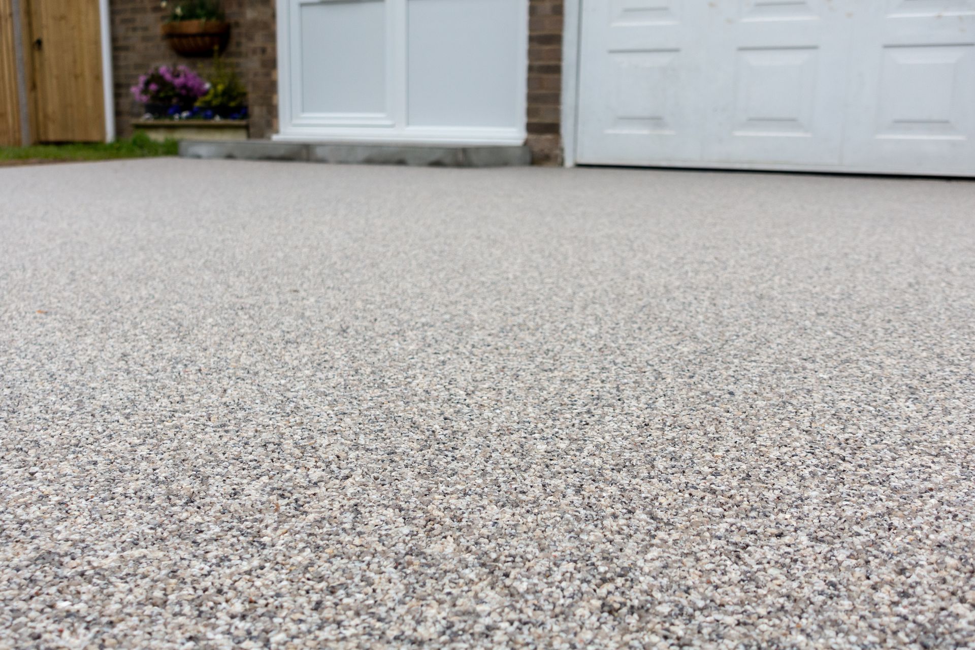 Close-up of a speckled concrete driveway leading to a front door and garage doors