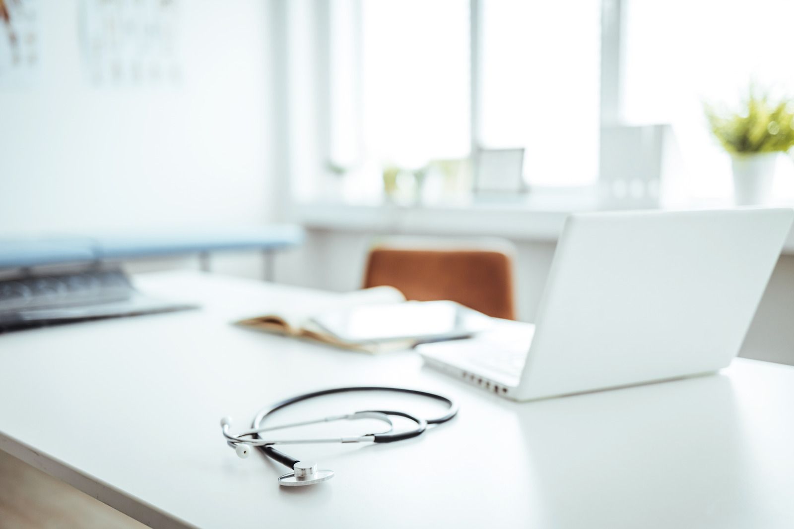 Laptop and eyeglasses on a bright white desk in a modern office