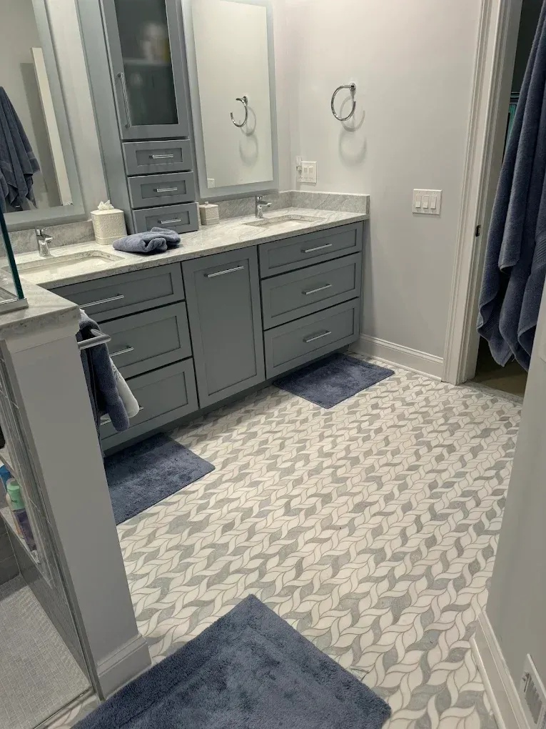 Bathroom with gray vanity, two sinks, patterned floor, and blue accents.