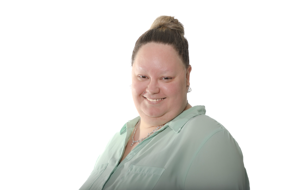 Personne souriante portant une chemise vert clair sur fond blanc.