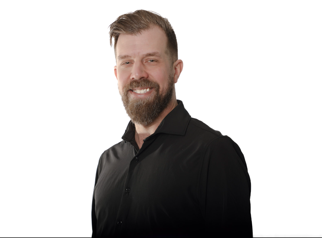 Homme souriant en chemise noire sur fond blanc