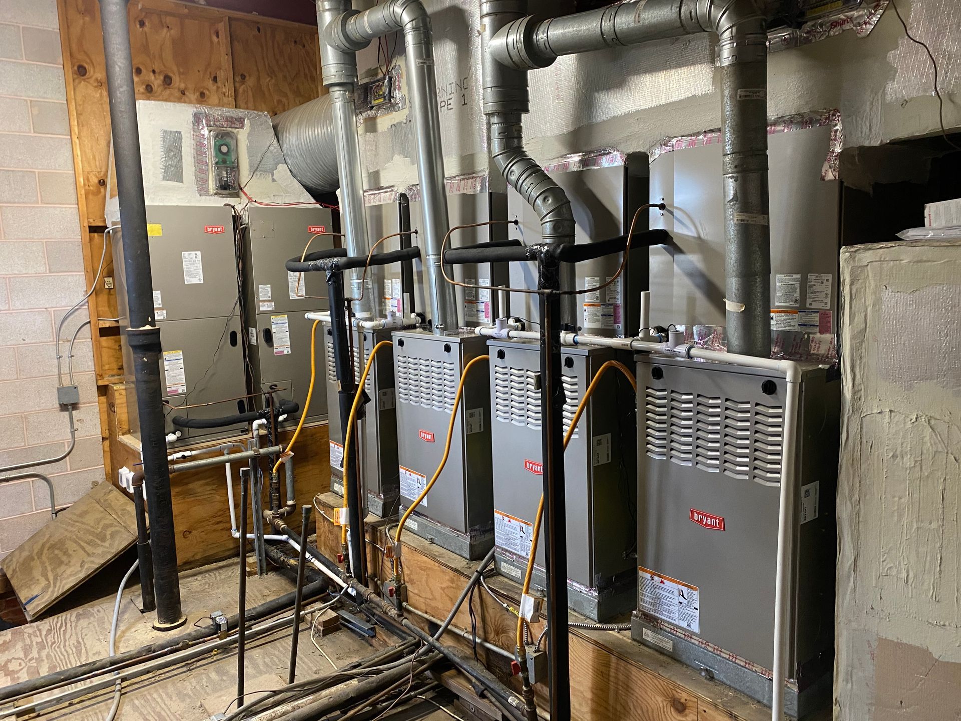 Several HVAC units with ductwork in a basement setting.