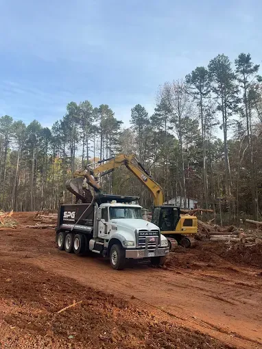 Excavator loading a dump truck at a wooded site