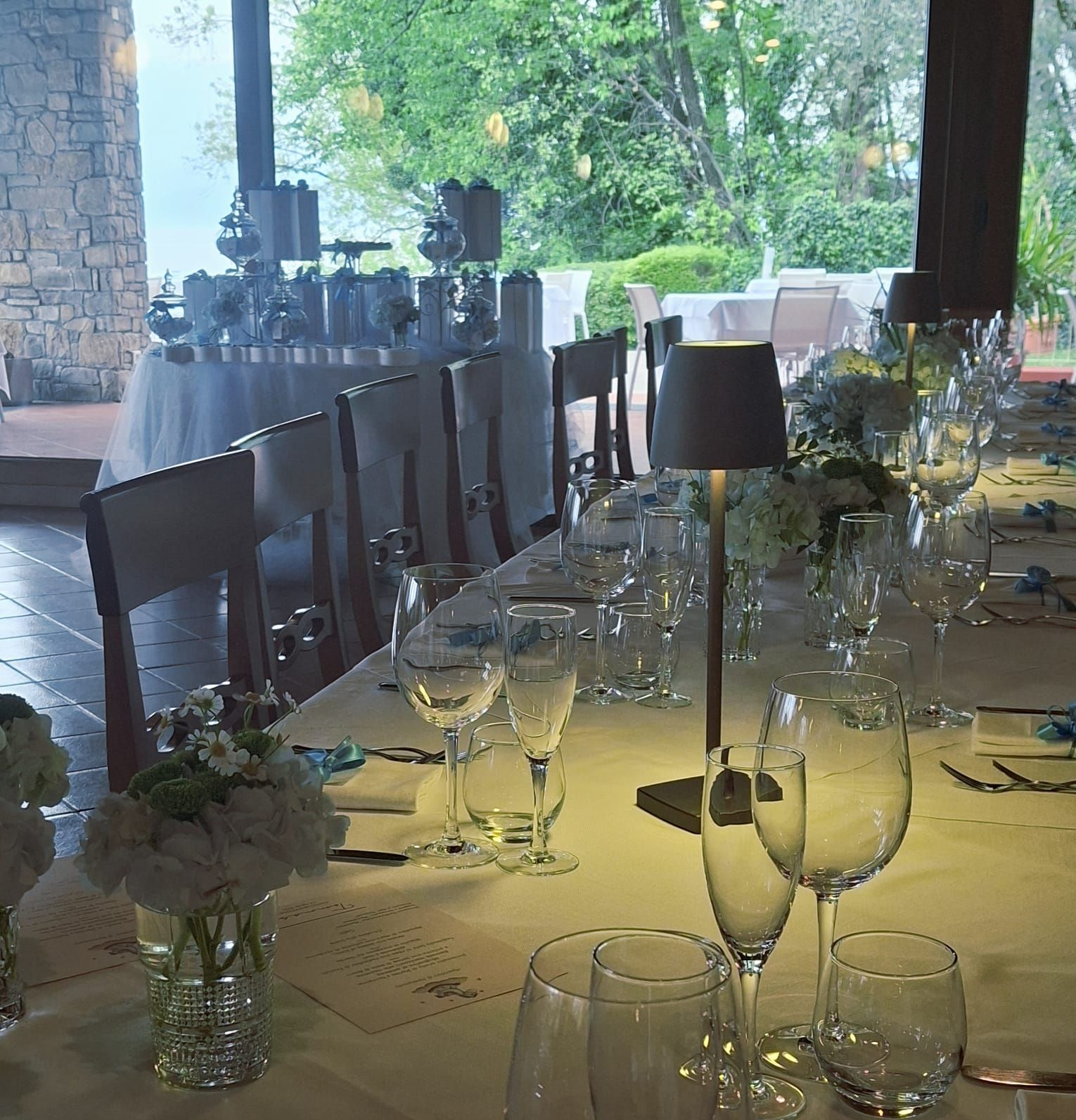 Sala da pranzo con tavoli e sedie ordinatamente apparecchiati, sotto calde travi di legno e ampie finestre.