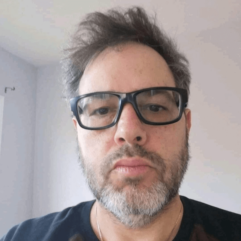 A man with glasses and a beard is looking at the camera.