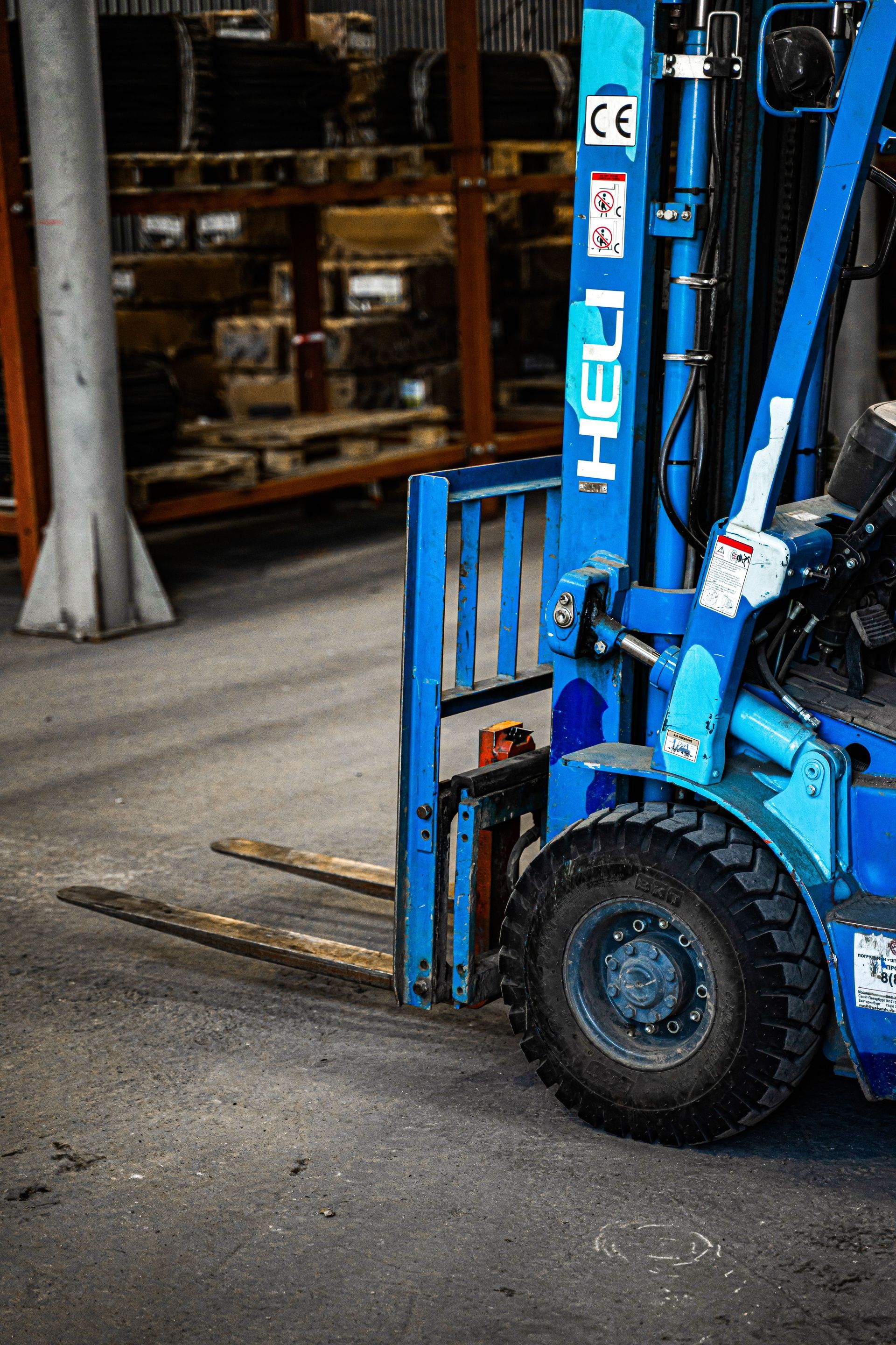 Blue forklift with wooden pallet in a warehouse aisle