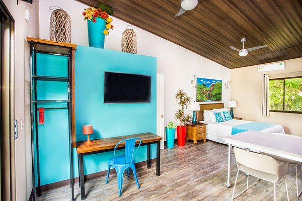 Modern living room with turquoise wall, wall-mounted TV, desk, and white sofa by large windows