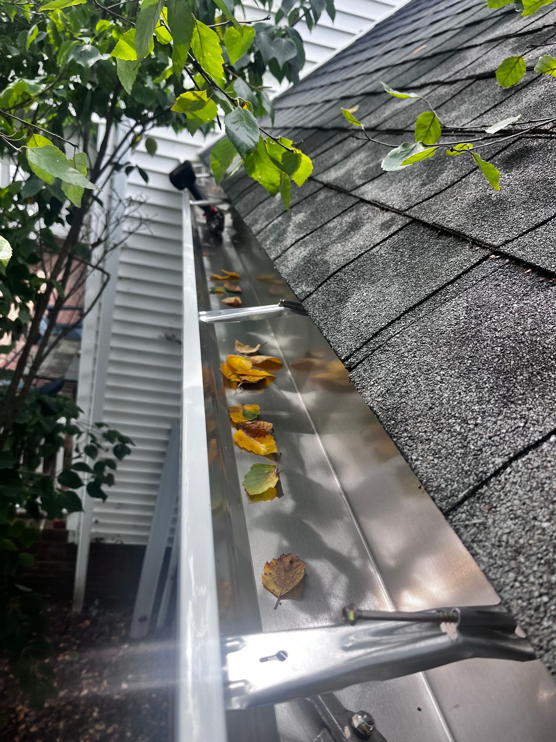 A man is installing a gutter on the side of a house.