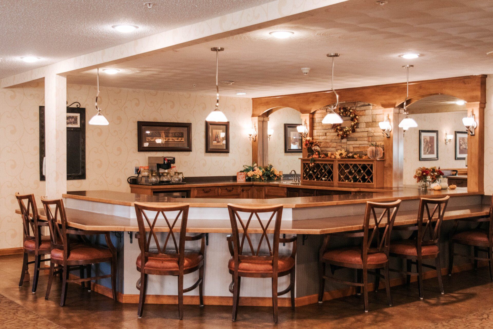 Bar with stools, wood counter and trim, pendant lights, framed art, wine rack.