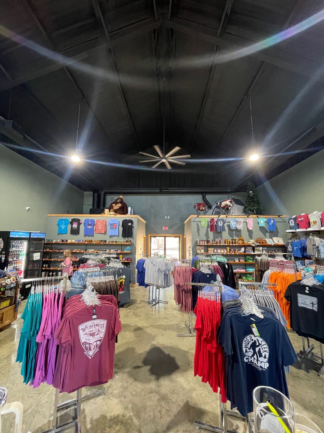 Clothing store interior with colorful hoodies and shirts on racks under a high ceiling