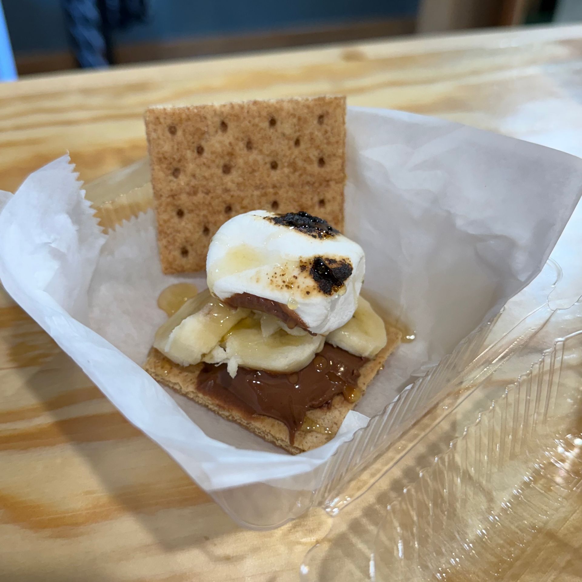 S'mores on a napkin: graham cracker, melted chocolate, banana, and toasted marshmallow with a cracker behind.