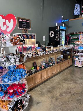 Toy store aisle with shelves of colorful plush toys and collectibles against gray walls