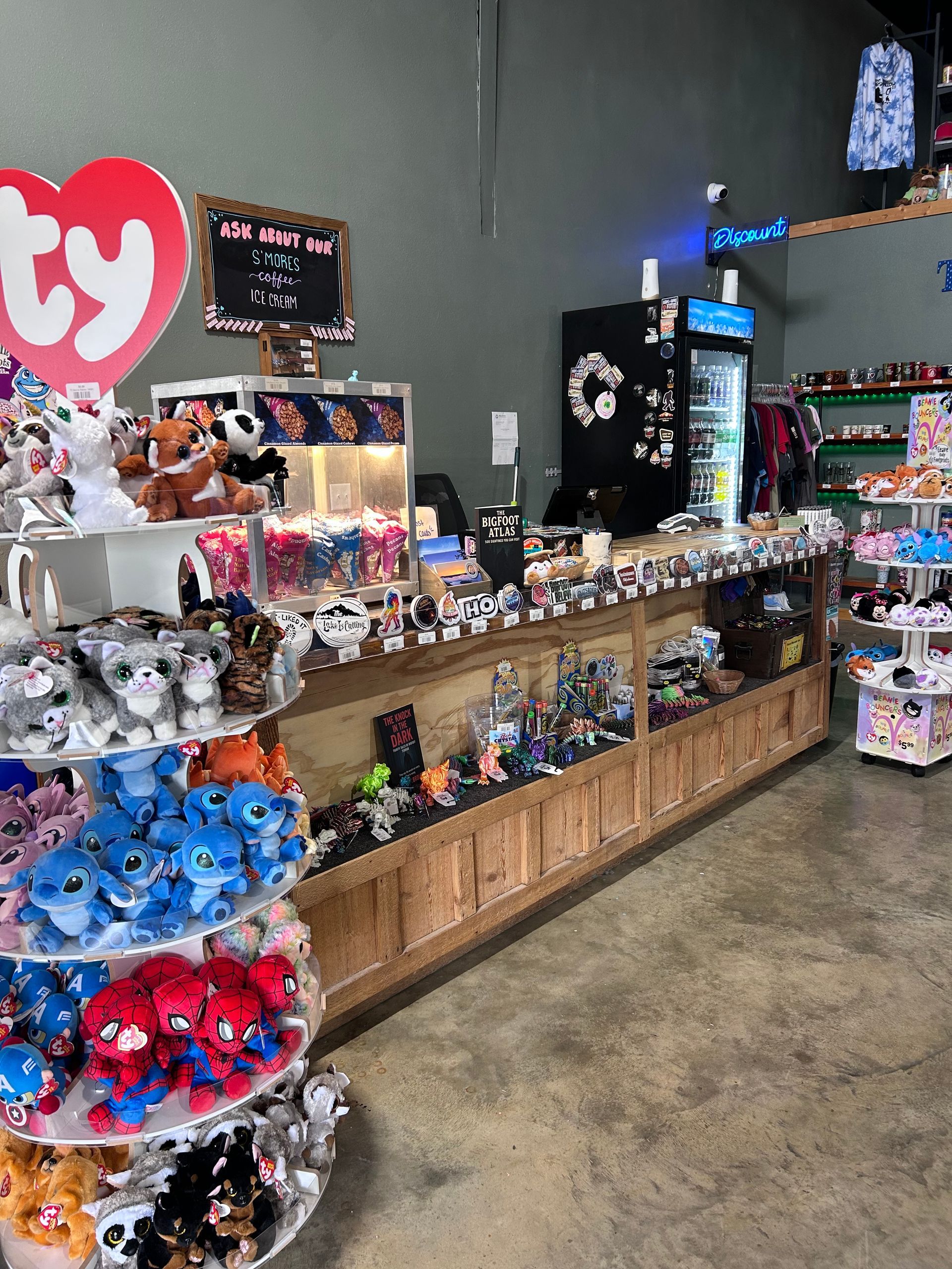 Gift shop display with rows of plush toys and trinkets on wooden shelves and a gray wall background
