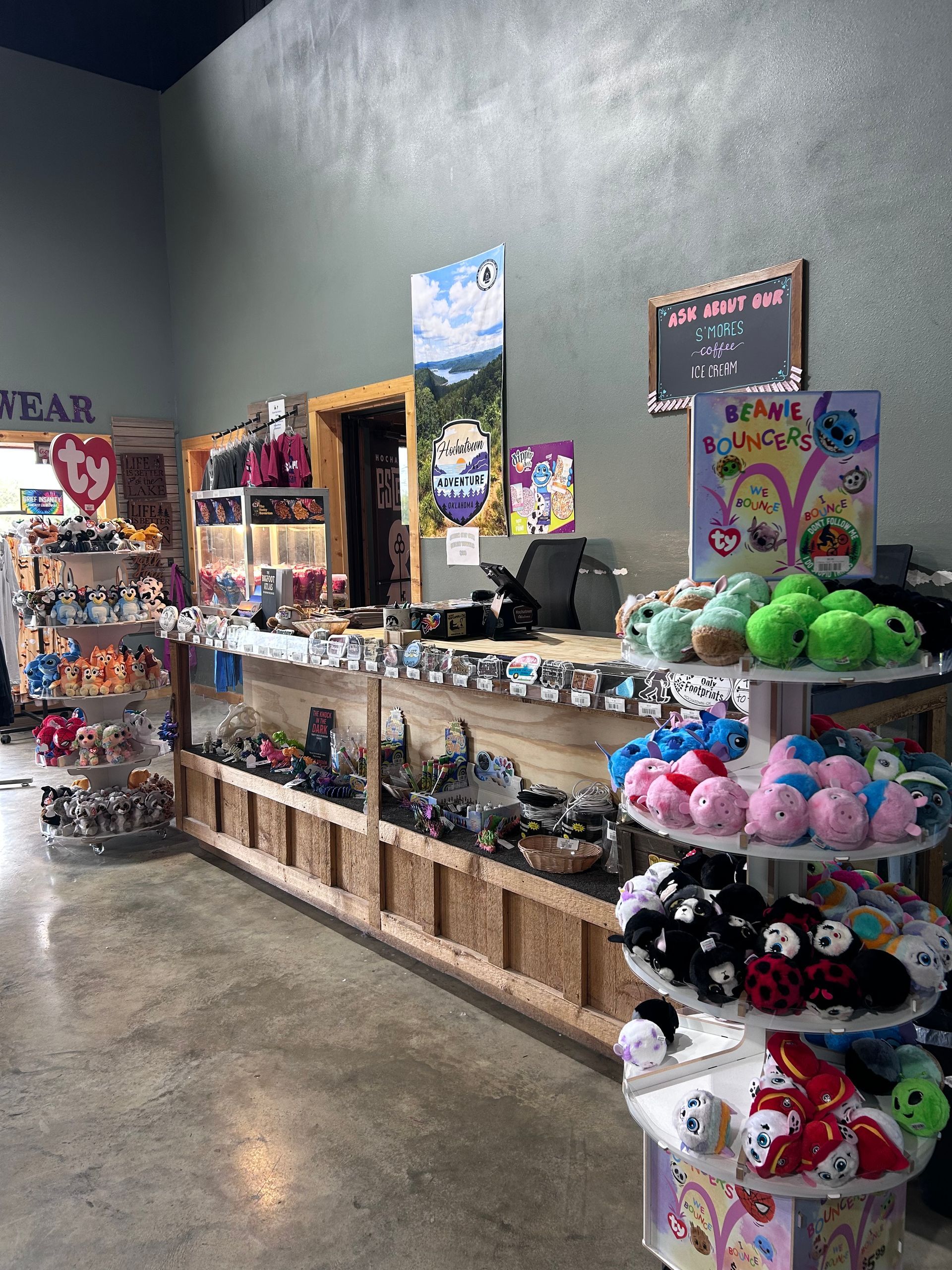 Gift shop display with shelves of stuffed animals and souvenirs against a dark gray wall.