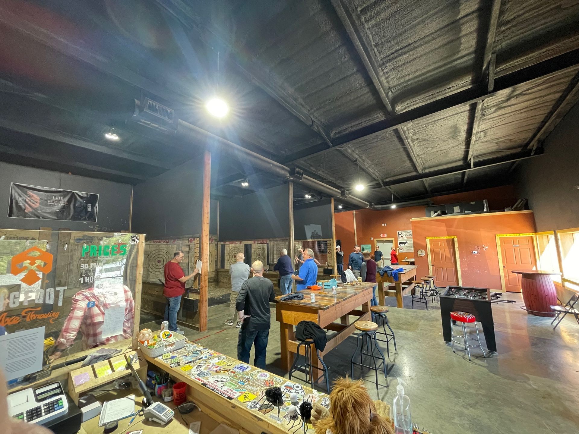 People browsing art and handmade goods in a warehouse-style market with tables and hanging lights
