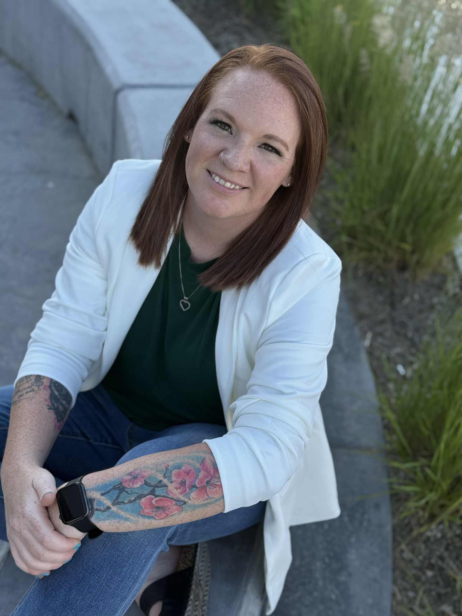 A woman is kneeling down in the grass in a park.