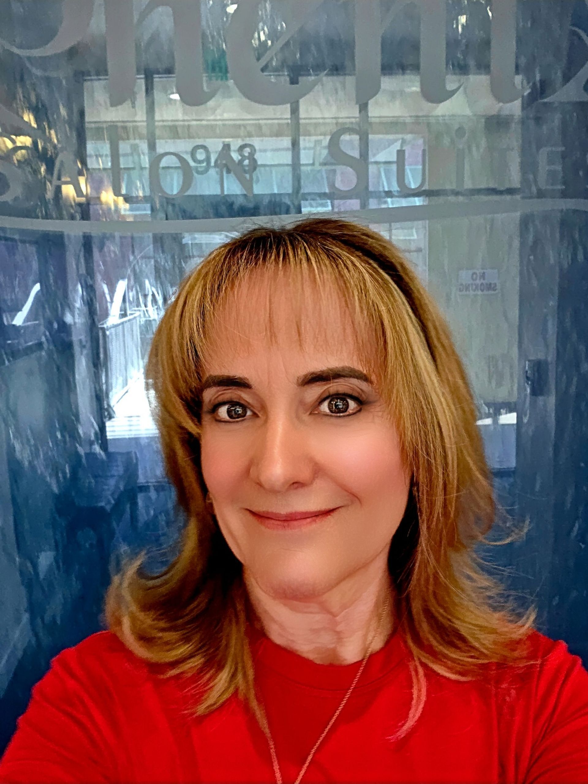 A woman in an orange dress and white shirt is smiling for the camera.