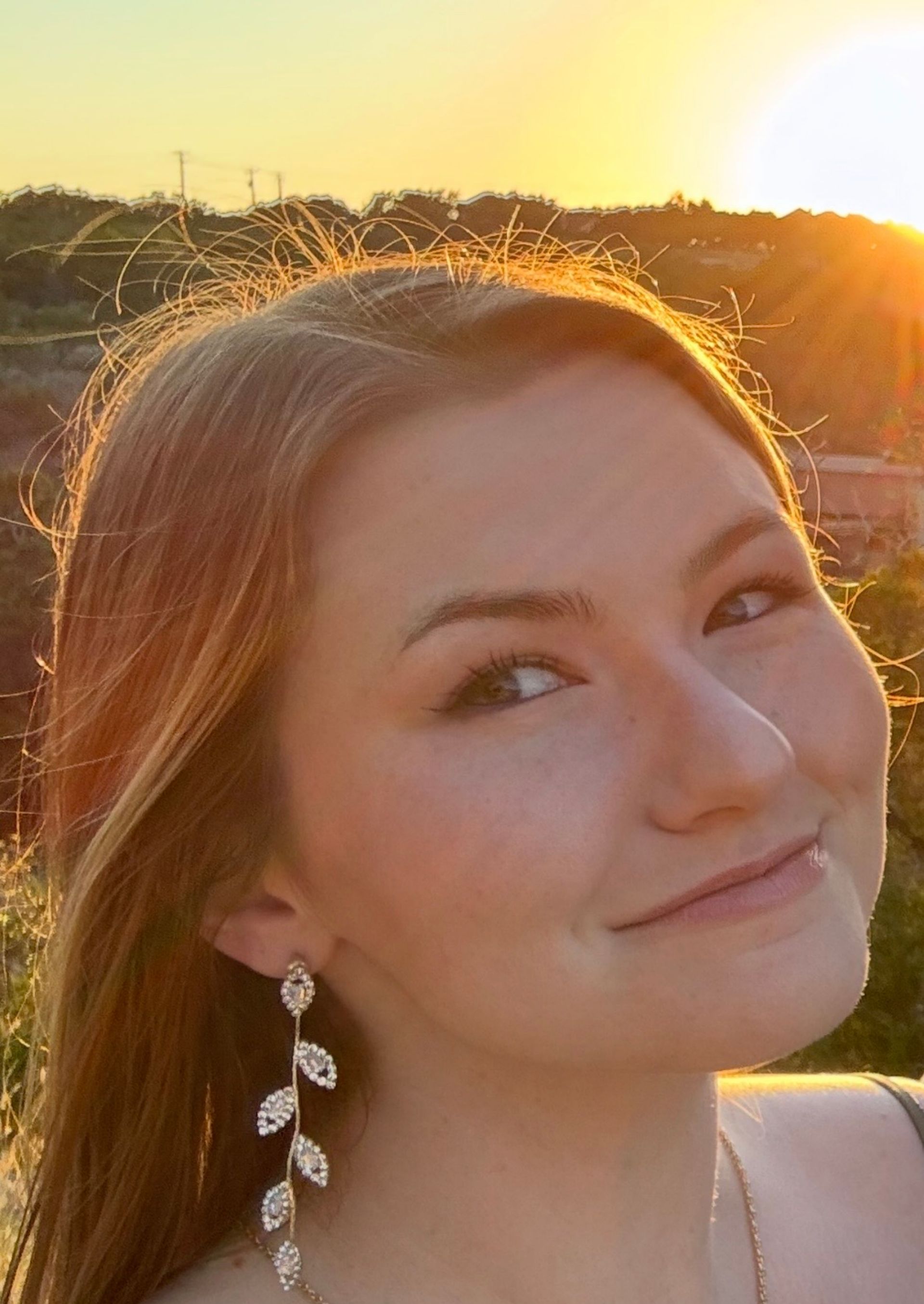 A woman in an orange dress and white shirt is smiling for the camera.