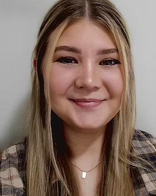 A woman wearing a plaid shirt and a necklace is smiling for the camera.