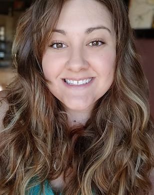 A woman with long curly hair is smiling for the camera.