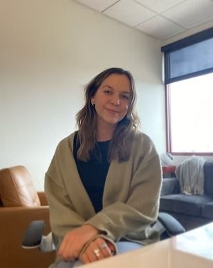 A woman is sitting at a desk in front of a window