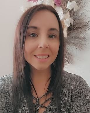 A woman is smiling for the camera in front of a wreath.
