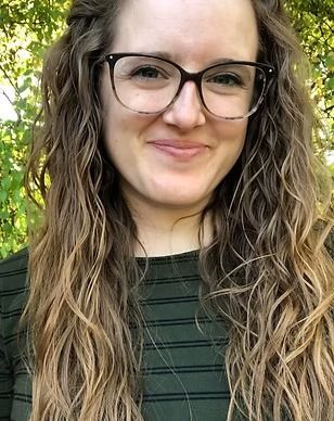 A woman wearing glasses and a striped shirt is smiling for the camera.