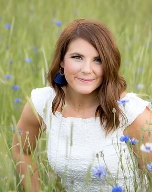 A woman in a white dress is sitting in a field of blue flowers.